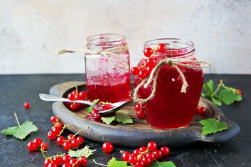 Red currant jam in curly glass jars on a black concrete background. Jam recipes. Harvest berries.