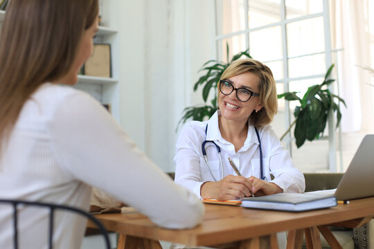 Middle Aged Female Doctor Therapist In Consultation With Patient In Office.