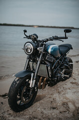 Fototapeta na wymiar Motorcycle is on sandy beach near water.