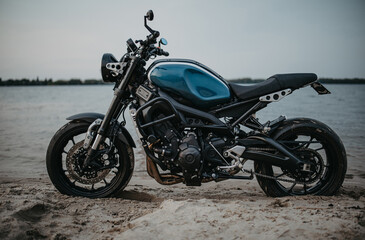 Fototapeta na wymiar Motorcycle is on sandy beach near water.