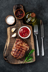 
Grilled beef steak with spices served on a cutting board on a stone background