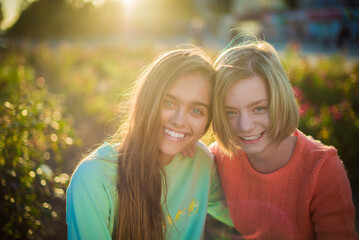 Fototapeta premium Two smiling girls. Two friends. Happy female students having fun together. Two young girls in the evening outside 