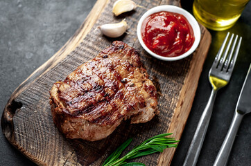 
Grilled beef steak with spices served on a cutting board on a stone background