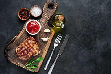 
Grilled beef steak with spices served on a cutting board on a stone background with copy space for your text
