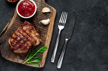 
Grilled beef steak with spices served on a cutting board on a stone background with copy space for...