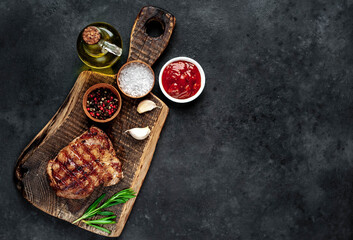 
Grilled beef steak with spices served on a cutting board on a stone background with copy space for your text