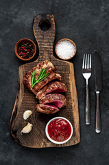 
Grilled beef steak with spices served on a cutting board on a stone background