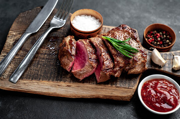 
Grilled beef steak with spices served on a cutting board on a stone background