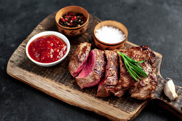 
Grilled beef steak with spices served on a cutting board on a stone background