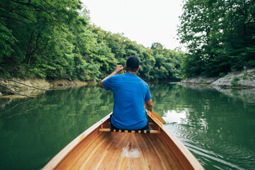 Fototapeta na wymiar Man paddling canoe in the forest lake