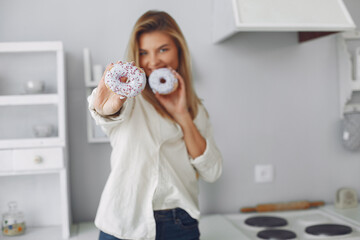 Girl in a white shirt. Lady in a kitchen. Girl with a donut