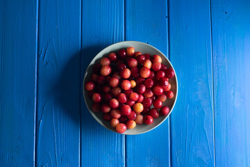 Ripe cherries in turquoise plate on wooden background