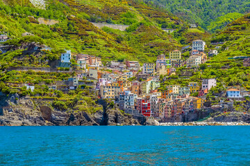 Fototapeta na wymiar A view from the sea towards the Cinque Terre coast and the village of Riomaggiore, Italy in the summertime