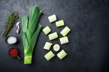 Chopped green leeks oninon uncooked with herbs ingredients , on textured black background top view...