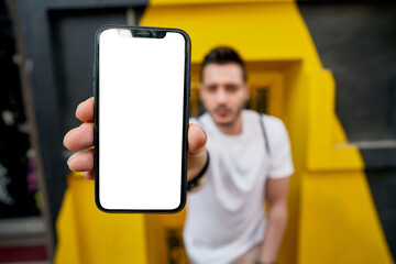Hipster guy showing cellphone device with copy space area for internet advertising, blurred...