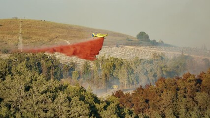 Fire fighter plane drops fire retardant on a forest fire in the hills