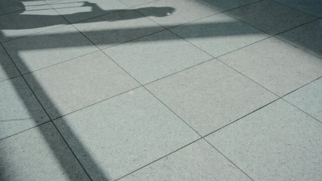 Shadow of traveller with suitcase on the tile floor of airport terminal. Concept travel transportation and logistics. Social distancing and safe space between passengers in new normal empty airport