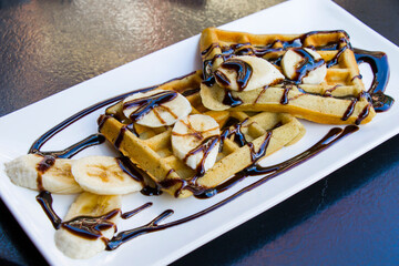 French pancake with banana and chocolate on the white plate