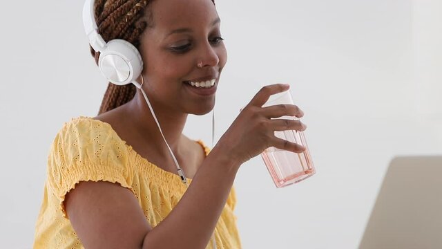 Black Woman Listening To Story That Her Friend Is Telling Through Laptop Video Call. Spbi. Teen Young Adult Girl Holding Glass Of Water And Chatting Smiling Online. Long Distance Friendship