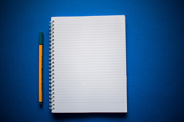 Top view of notebook with pen on blue background