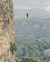 A man is walking along a stretched sling. Highline in the mountains. Man catches balance....