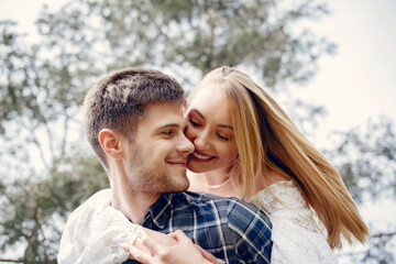 Cute couple in a park. Lady in a white dress. Guy in a blue shirt
