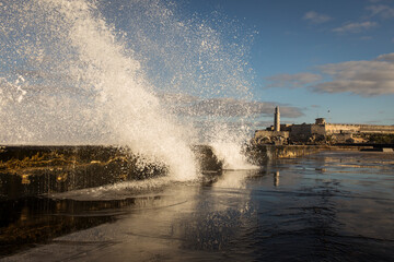 Big waves on Malecon streets during sunrise with storm clouds in background. Havana, Cuba