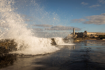 Big waves on Malecon streets during sunrise with storm clouds in background. Havana, Cuba