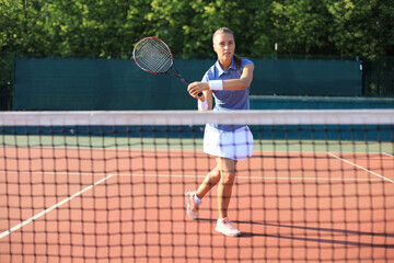 Professional equipped female tennis player beating hard the tennis ball with racquet.