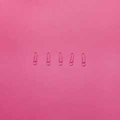 Pink paper clips on the pink background. Horizontal