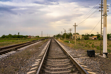 Obraz na płótnie Canvas Railway at sunset. Railroad station. Railroad crossing. Railway signs at the crossroads. Sky with rain clouds at sunset. Clouds in the sky. Rails, sleepers, stones. Perspective. Horizon