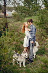 Naklejka na ściany i meble Couple in a forest. Pair with cute dogs. Lady in a white dress