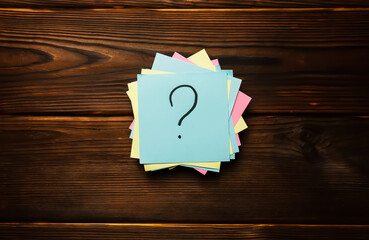 Paper stickers with a question mark on a wooden background