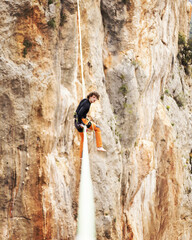 A man is walking along a stretched sling. Highline in the mountains. Man catches balance. Performance of a tightrope walker in nature. Highliner on the background of valley.