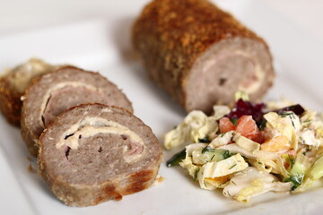 Meat roulade with salad on plate. Rolled meat with a filling of cheese and ham.