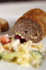 Meat roulade with salad on plate. Rolled meat with a filling of cheese and ham.