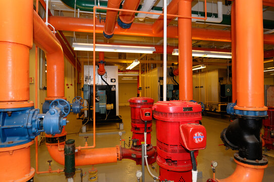 Row Of Furnaces And Hot Water Pipes In The Boiler Room Of A Highrise Office Building