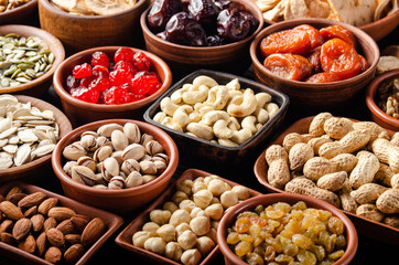 Different nuts seeds and dried fruits in bowls on wooden kitchen table