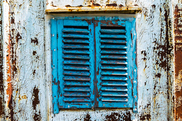 Old wooden window painted blue with rusty lock. Texture, wall of an old wooden house with shuttered windows, painted blue. 