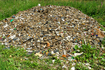 A large gray pile of garbage in the middle of a wonderful field, an illustration of environmental pollution in Russia