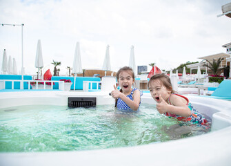 Two little cute girls play in the pool.