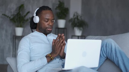 Online education, distance training, business meeting, webinar conference. African American man participating in a webinar while sitting on a sofa with a laptop