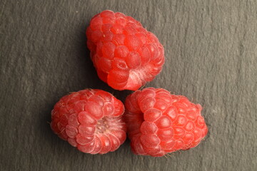 Juicy organic raspberries, close-up, on a slate board.