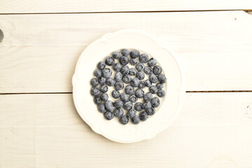 Ripe juicy organic blueberries, close-up, on a white wooden table.