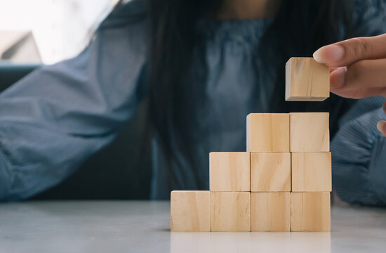 plan and strategy in business.risk concept.hand of woman has piling up and stacking a wooden block.Businesswoman Building The Success.