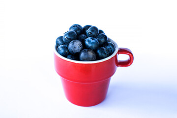 Red cup of bilberries and blueberries on a white background. Berry with water drop.