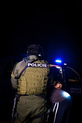 A police officer puts handcuffs on a criminal's hands during an arrest. Police car with flashing lighthouses