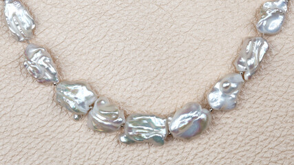 Curve of baroque pearls on beige leather background