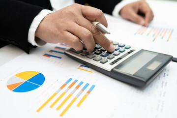 Asian accountant working and analyzing financial reports project accounting with chart graph and...
