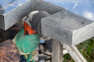 Grinding marble with a grinder. A woman's hand in a cloth, protective gloves holds the grinder. Grinding marble with a grinder. The manufacture of the monument.